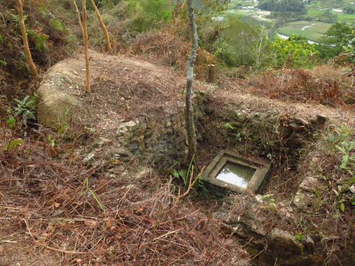 Inside a stone wall revetted enclosure, a 2-metre deep concrete shaft was constructed near a large rectangular pillbox close to the top of the knoll on the western side. Square in plan and with steel rungs for access on its southern side, its purpose has yet to be determined. Possible uses might have been water supply, field sanitation or some sort of shelter. (photo credit: The University of Hong Kong) 